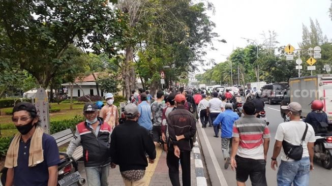 Warga meluber ke jalan raya saat mengejar mobil yang mengangkut sembako Presiden Jokowi di Terminal Grogol, Jakarta Barat. (Suara.com/Yaumal)