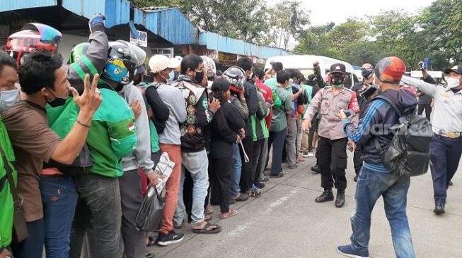 Kerumunan warga saat mengantre sembako yang dibagikan Presien Jokowi di Terminal Grogol, Jakbar. (Suara.com/Yaumal)