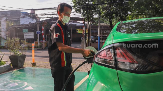 Petugas menaruh kontak tusuk ke kendaraan untuk melakukan pengisian daya di Stasiun Pengisian Kendaraan Listrik Umum (SPKLU) di Kawasan MT. Haryono, Jakarta Selatan, Rabu (11/8/2021). [Suara.com/Alfian Winanto]