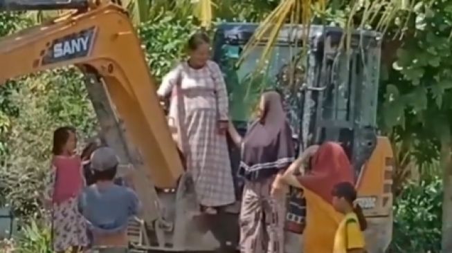 Ibu-ibu Pose Naik Ekskavator Viral, Publik: Bahagia Itu Sederhana