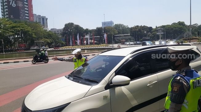 Polisi saat mencegat pengendara mobil di kawasan sistem ganjil genap di Medan Merdeka Barat. (Suara.com/Yaumal)