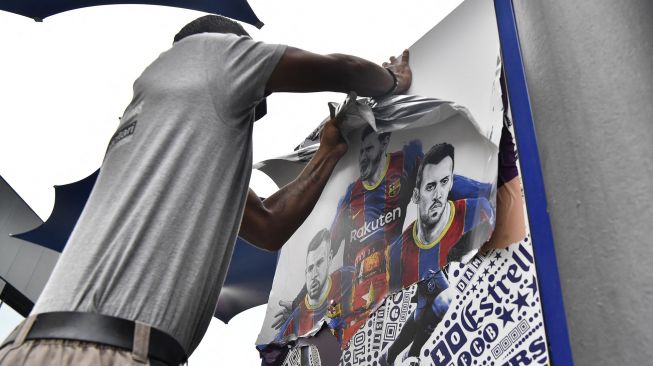 Pekerja melepas poster-poster Lionel Messi di Stadion Camp Nou, Barcelona, Spanyol, (10/8/2021).  [AFP Photo]