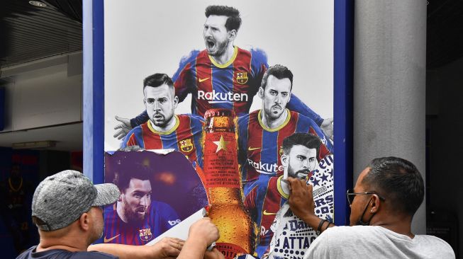 Pekerja melepas poster-poster Lionel Messi di Stadion Camp Nou, Barcelona, Spanyol, (10/8/2021).  [AFP Photo]