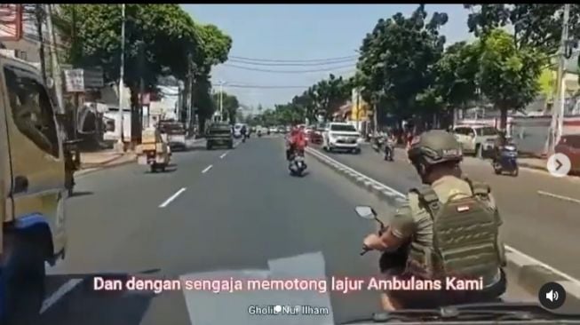 Pria berseragam coklat menghambat laju mobil ambulans yang membawa bayi dalam keadaan kritis (Instagram)