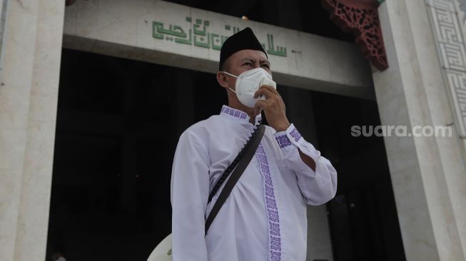 Pengurus masjid memberikan imbauan untuk mematuhi protokol kesehatan kepada jamaah yang akan menunaikan sholat Jumat berjamaah di Masjid At-Tin, Jakarta, Jumat (13/8/2021). [Suara.com/Angga Budhiyanto]