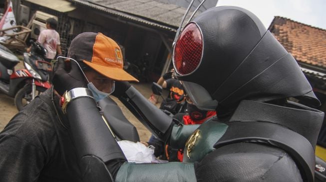 Relawan mengenakan kostum superhero satria baja hitam membagikan makanan dan masker kepada pemulung di Grand Depok City, Depok, Jawa Barat, Jumat (13/8/2021). [ANTARA FOTO/Asprilla Dwi Adha]