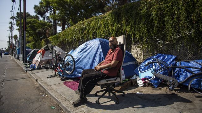 Albert Martinez, yang telah hidup selama 20 tahun di jalanan Los Angeles, duduk di luar tendanya di trotoar di Venesia, California, Amerika Serikat, pada (12/8/2021). [Apu GOMES / AFP]