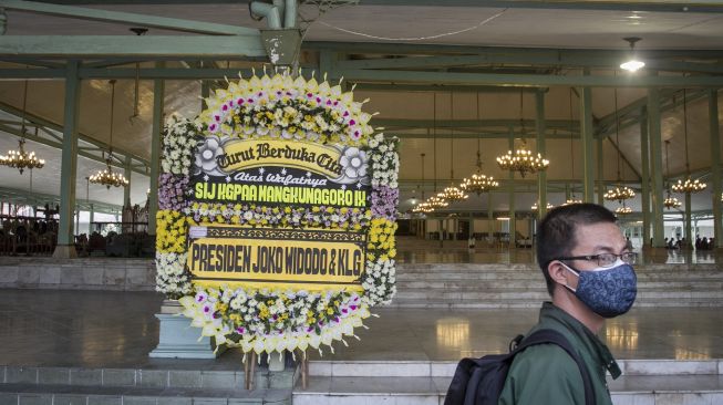 Seorang warga melintas di depan karangan bunga ucapan duka cita almarhum Kanjeng Gusti Pangeran Adipati Arya (KGPAA) Mangkunagoro IX di Pura Mangkunegaran, Solo, Jawa Tengah, Jumat (13/8/2021). [ANTARA FOTO/Mohammad Ayudha]