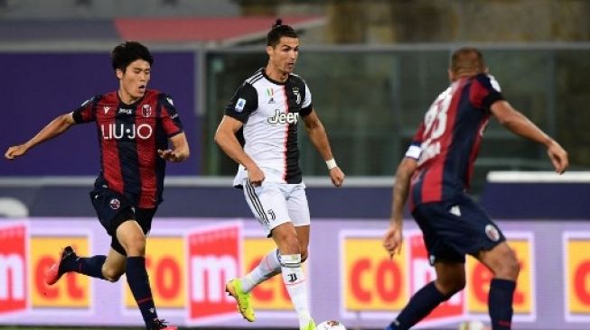 Aksi bek Bologna asal Jepang, Takehiro Tomiyasu saat berhdapan dengan bintang Juventus, Cristiano Ronaldo. (MIGUEL MEDINA / AFP)