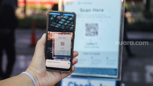 Warga memindai QR Code untuk pendataan sebelum masuk ke Pondok Indah Mall, Jakarta Selatan, Minggu (15/8/2021). [Suara.com/Alfian Winanto]