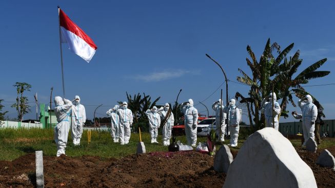 Sejumlah relawan pemakaman jenazah protokol COVID-19 dengan mengenakan Alat Pelindung Diri (APD) melakukan upacara bendera dalam rangka peringatan Hari Ulang Tahun ke-76 Proklamasi Kemerdekaan RI di Pemakaman Pagu Indah Kota Madiun, Jawa Timur, Minggu (15/8/2021).  ANTARA FOTO/Siswowidodo