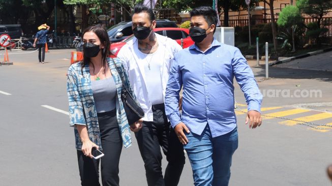 Musisi I Gede Ari Astina alias Jerinx SID ditemani sang istri, Nora Alexandra saat datang untuk menjalani vaksinasi Covid-19 di Polda Metro Jaya, Jakarta, Minggu (15/8/2021). [Suara.com/Alfian Winanto]