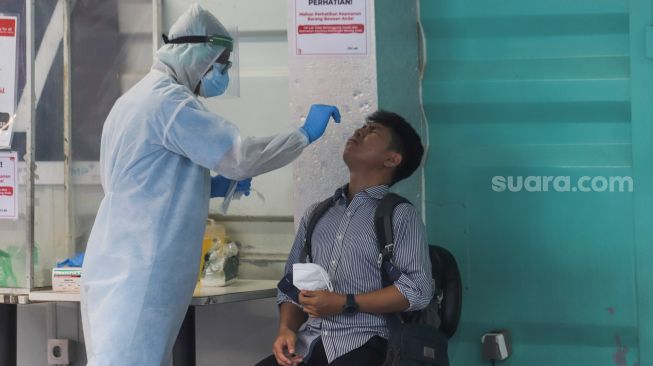 Petugas melakukan swab PCR kepada warga di GSI Lab, Jakarta Selatan, Senin (16/8/2021). [Suara.com/Alfian Winanto]