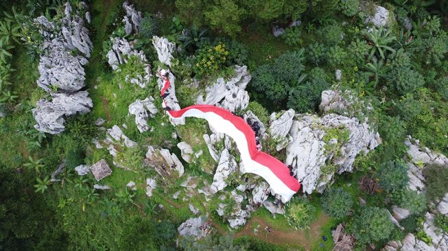 Bendera raksasa ukuran 45x4 meter dibentangkan di atas tebing batu dengan ketinggian 800 mdpl, Senin (16/8/2021). [Suara.com/Citra Ningsih]