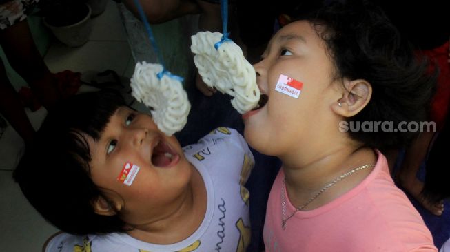 Anak-anak mengikuti lomba makan kerupuk di Menteng, Jakarta, Selasa (17/8).  [Suara.com/Oke Atmaja]
