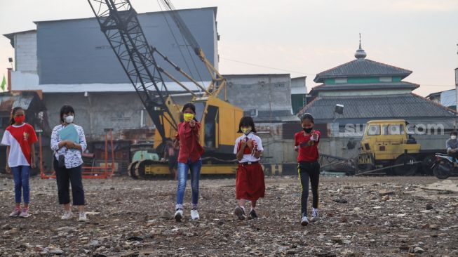 Anak-anak dari Komunitas Kelas Jurnalis Cilik melakukan upacara bendera HUT RI ke-76 di Belah Kapal, Cilincing, Jakarta Utara, Selasa (17/8/2021). [Suara.com/Alfian Winanto]