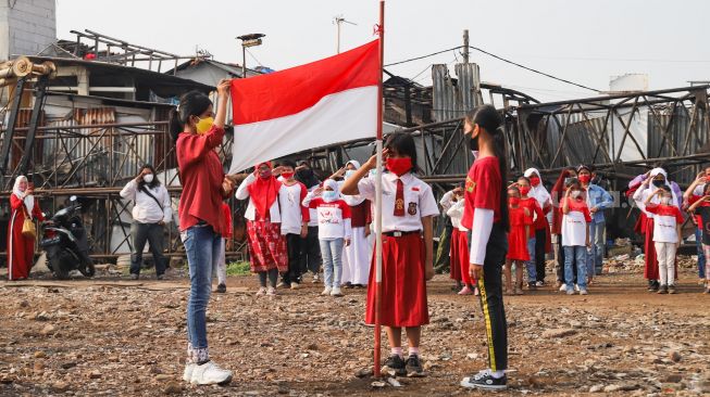 Anak-anak dari Komunitas Kelas Jurnalis Cilik melakukan upacara bendera HUT RI ke-76 di Belah Kapal, Cilincing, Jakarta Utara, Selasa (17/8/2021). [Suara.com/Alfian Winanto]