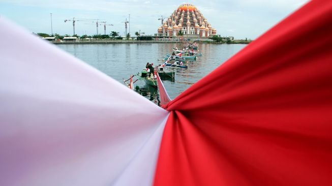 Sejumlah anggota TNI, Polri dan nelayan membentangkan bendera merah putih di perairan Pantai Losari, Makassar, Sulawesi Selatan, Selasa (17/8/2021). ANTARA FOTO/Arnas Padda