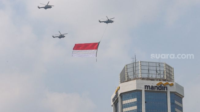 Bendera Merah Putih raksasa yang dikibarkan menggunakan helikopter TNI Angkatan Udara mengelilingi Jakarta, Selasa (13/8/2021). [Suara.com/Alfian Winanto]