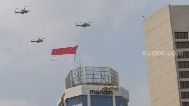 Bendera Merah Putih raksasa yang dikibarkan menggunakan helikopter TNI Angkatan Udara mengelilingi Jakarta, Selasa (13/8/2021). [Suara.com/Alfian Winanto]