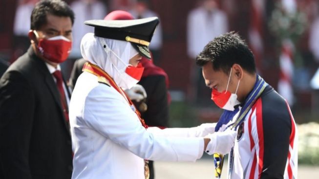 Gubernur Jatim Khofifah Indar Parawansa menyematkan tanda kehormatan Lencana Jer Basuki Mawa Beya Emas kepada lifter Eko Yuli Irawan usai upacara pengibaran bendera memperingati HUT Ke-76 RI di Gedung Negara Grahadi di Surabaya, Selasa (17/8/2021). (ANTARA/HO-Biro Adpim Jatim)