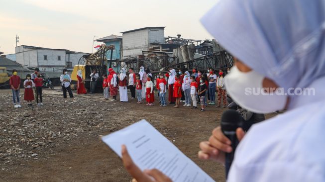 Anak-anak dari Komunitas Kelas Jurnalis Cilik melakukan upacara bendera HUT RI ke-76 di Belah Kapal, Cilincing, Jakarta Utara, Selasa (17/8/2021). [Suara.com/Alfian Winanto]