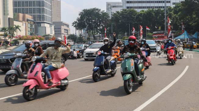 Komunitas Motor Vespa melintas di kawasan Bundaran Hotel Indonesia (HI), Jakarta Pusat, Selasa (17/8/2021). [Suara.com/Alfian Winanto]