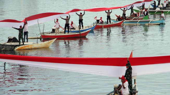 Sejumlah anggota TNI, Polri dan nelayan membentangkan bendera merah putih di perairan Pantai Losari, Makassar, Sulawesi Selatan, Selasa (17/8/2021). ANTARA FOTO/Arnas Padda