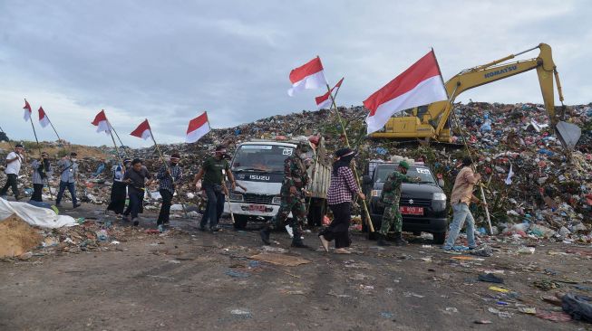 Sejumlah jurnalis dari berbagai media yang tergabung dalam Komunitas Pena Emas Aceh bersama TNI membawa bendera berjalan menuju daerah ketinggian di Bukit Pengolahan Sampah kawasan pesisir pantai, Kampung Jawa, Banda Aceh, Senin (16/8/2021).  ANTARA FOTO/Ampelsa