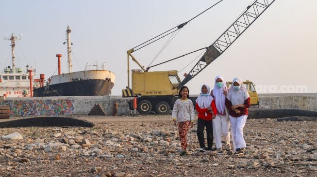 Anak-anak dari Komunitas Kelas Jurnalis Cilik saat datang untuk melakukan upacara bendera HUT RI ke-76 di Belah Kapal, Cilincing, Jakarta Utara, Selasa (17/8/2021). [Suara.com/Alfian Winanto]