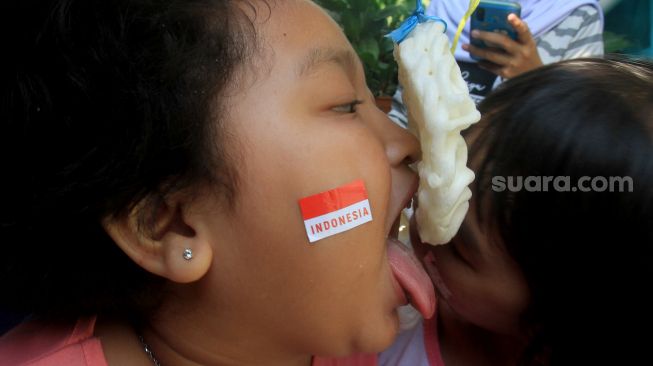 Anak-anak mengikuti lomba makan kerupuk di Menteng, Jakarta, Selasa (17/8).  [Suara.com/Oke Atmaja]
