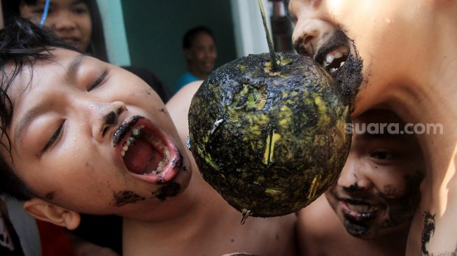 Anak-anak mengikuti lomba mengambil uang dari buah melon di Menteng, Jakarta, Selasa (17/8).  [Suara.com/Oke Atmaja]
