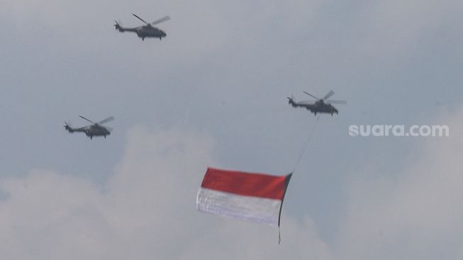 Bendera Merah Putih raksasa yang dikibarkan menggunakan helikopter TNI Angkatan Udara mengelilingi Jakarta, Selasa (13/8/2021). [Suara.com/Alfian Winanto]