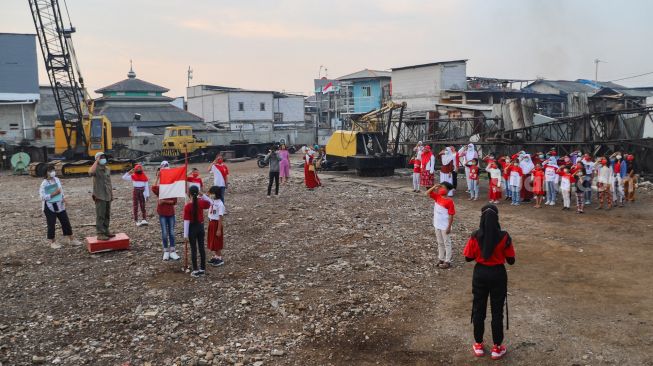 Anak-anak dari Komunitas Kelas Jurnalis Cilik melakukan upacara bendera HUT RI ke-76 di Belah Kapal, Cilincing, Jakarta Utara, Selasa (17/8/2021). [Suara.com/Alfian Winanto]