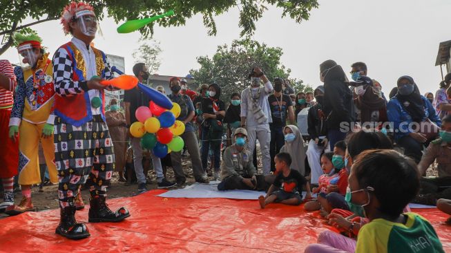 Sejumlah Badut yang tergabung dalam komunitas Aku Badut Indonesia (ABI) menghibur anak-anak di pengungsian korban kebakaran di Jl. Kemang Utara IX, Jakarta Selatan, Rabu (18/8/2021). [Suara.com/Alfian Winanto]