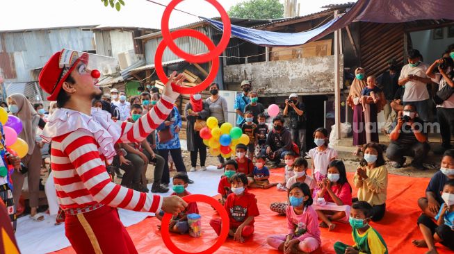 Badut yang tergabung dalam komunitas Aku Badut Indonesia (ABI) menghibur anak-anak di pengungsian korban kebakaran di Jl. Kemang Utara IX, Jakarta Selatan, Rabu (18/8/2021). [Suara.com/Alfian Winanto]