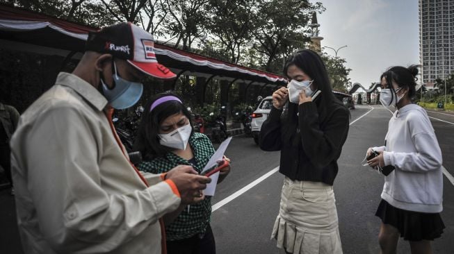 Petugas (kiri) memeriksa sertifikat vaksin COVID-19 milik pengunjung di pintu masuk Taman Impian Jaya Ancol, Jakarta, Rabu (18/8/2021). ANTARA FOTO/Aprillio Akbar