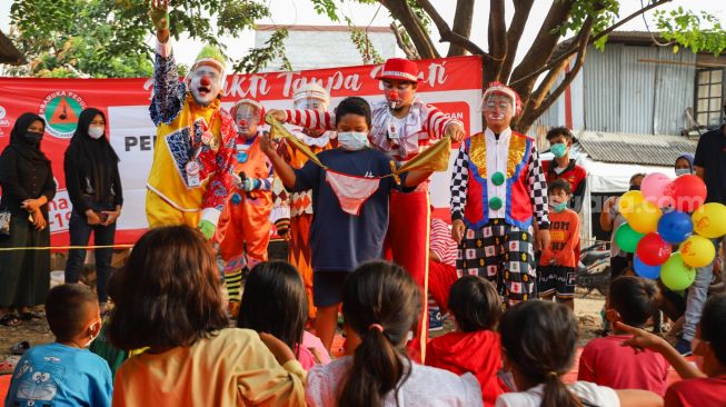 Sejumlah Badut yang tergabung dalam komunitas Aku Badut Indonesia (ABI) mengajak bermain anak-anak di pengungsian korban kebakaran di Jl. Kemang Utara IX, Jakarta Selatan, Rabu (18/8/2021). [Suara.com/Alfian Winanto]