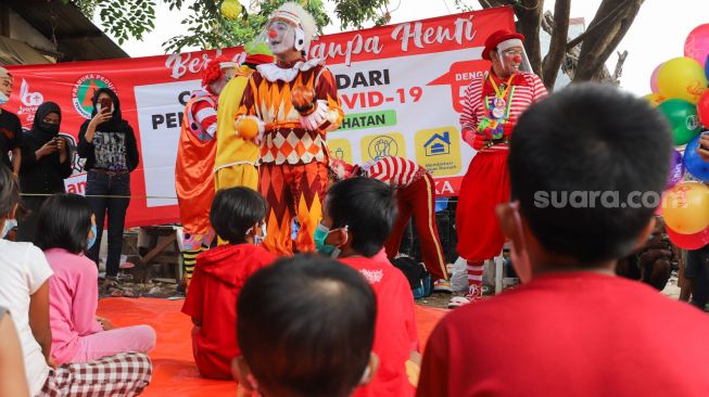 Sejumlah Badut yang tergabung dalam komunitas Aku Badut Indonesia (ABI) menghibur anak-anak di pengungsian korban kebakaran di Jl. Kemang Utara IX, Jakarta Selatan, Rabu (18/8/2021). [Suara.com/Alfian Winanto]