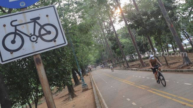 Warga berolahraga sepeda di Jalur Banjir Kanal Timur, Jakarta Timur, Kamis (19/8/2021). [Suara.com/Alfian Winanto]