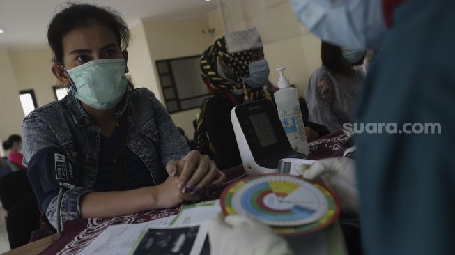 Petugas kesehatan memeriksa kondisi kesehatan ibu hamil sebelum memberikan vaksinasi COVID-19 di Kantor Kelurahan Cipayung, Jakarta, Kamis (19/8/2021). [Suara.com/Angga Budhiyanto]