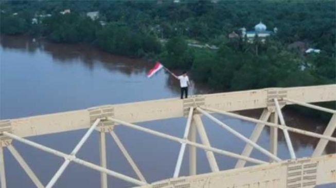 Aksi warga Siak mengibarkan bendera merah putih dari puncak jembatan. [Tangkapan layar]