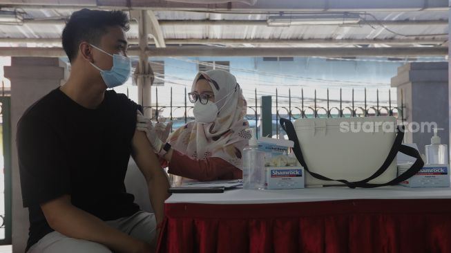 Vaksinator menyuntikkan vaksin COVID-19 pada warga di Stasiun Juanda, Jakarta, Jumat (20/8/2021). [Suara.com/Angga Budhiyanto]
