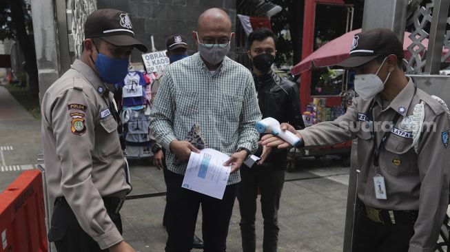 Petugas memeriksa sertifikat vaksin jamaah yang akan menunaikan sholat Jumat berjamaah di Masjid Istiqlal, Jakarta, Jumat (20/8/2021). [Suara.com/Angga Budhiyanto]