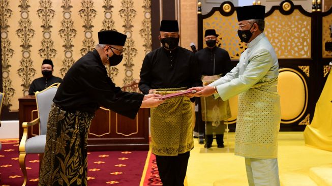 Perdana Menteri Malaysia yang akan datang Ismail Sabri Yaakob (kiri) menerima dokumen dari Raja Sultan Abdullah Sultan Ahmad Shah (kanan) sebelum mengambil sumpah sebagai pemimpin baru negara itu di Istana Negara, Kuala Lumpur, Malaysia, Sabtu (21/9).  [AFP/Photo]