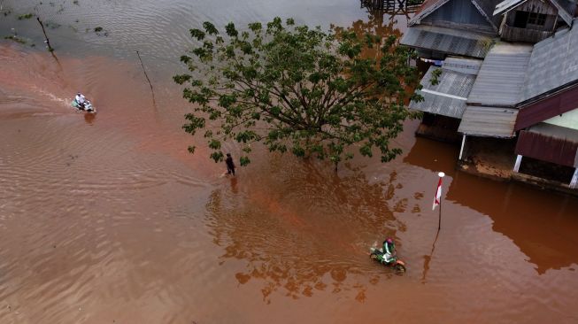 Foto udara warga menerobos banjir di Desa Wonoamonapa, Kecamatan Pondidaha, Konawe, Sulawesi Tenggara, Sabtu (21/8/2021). [ANTARA FOTO/Jojon]