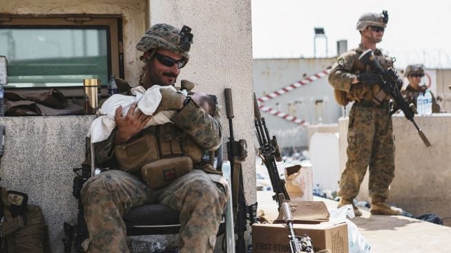 Marinir AS yang ditugaskan di Unit Ekspedisi Kelautan (MEU) ke-24 menggendong bayi saat evakuasi di Bandara Internasional Hamid Karzai, Kabul, Afghanistan, dalam foto yang diambil Jumat (20/8/2021). [AFP Photo]