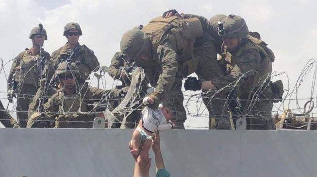 Bayi diserahkan kepada tentara Amerika melewati dinding perimeter bandara menunggu untuk dievakuasi, di Kabul, Afghanistan, Kamis (19/8/2021). [AFP Photo}