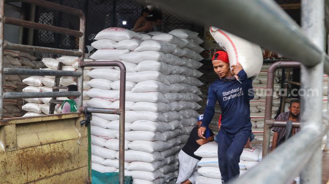 Pekerja mengangkut karung beras di Pasar Induk Beras, Cipinang, Jakarta Timur, Sabtu (21/8/2021). [Suara.com/Alfian Winanto]