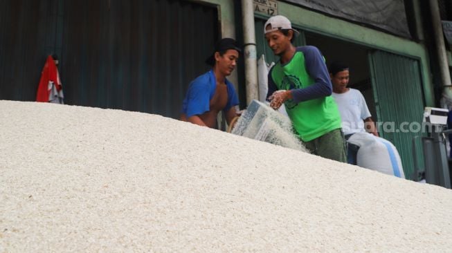 Pekerja memasukan beras kedalam karung di Pasar Induk Beras, Cipinang, Jakarta Timur, Sabtu (21/8/2021). [Suara.com/Alfian Winanto]